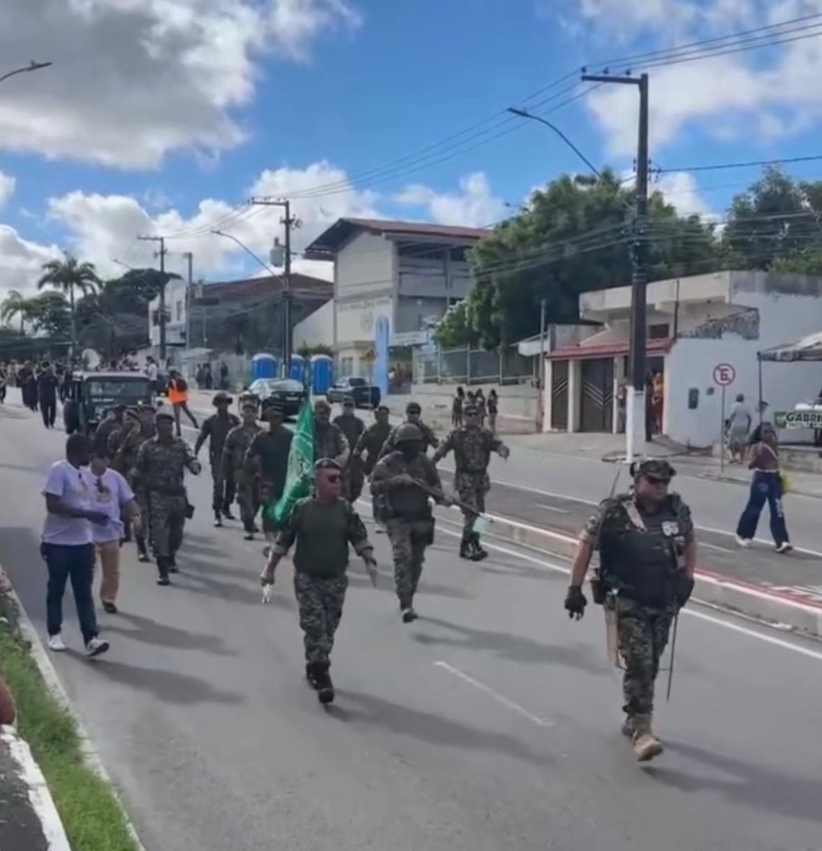 Grupo de veteranos do GVEB em trajes militares desfila por rua do bairro 18 do Forte, em Aracaju, carregando bandeira verde